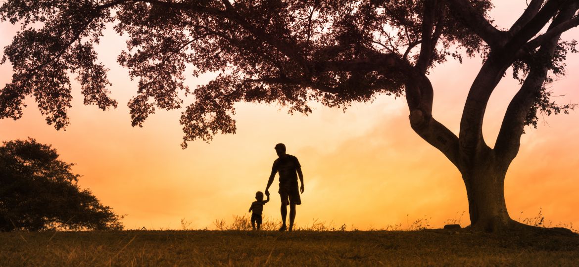 Father walking with is son at the park at sunset